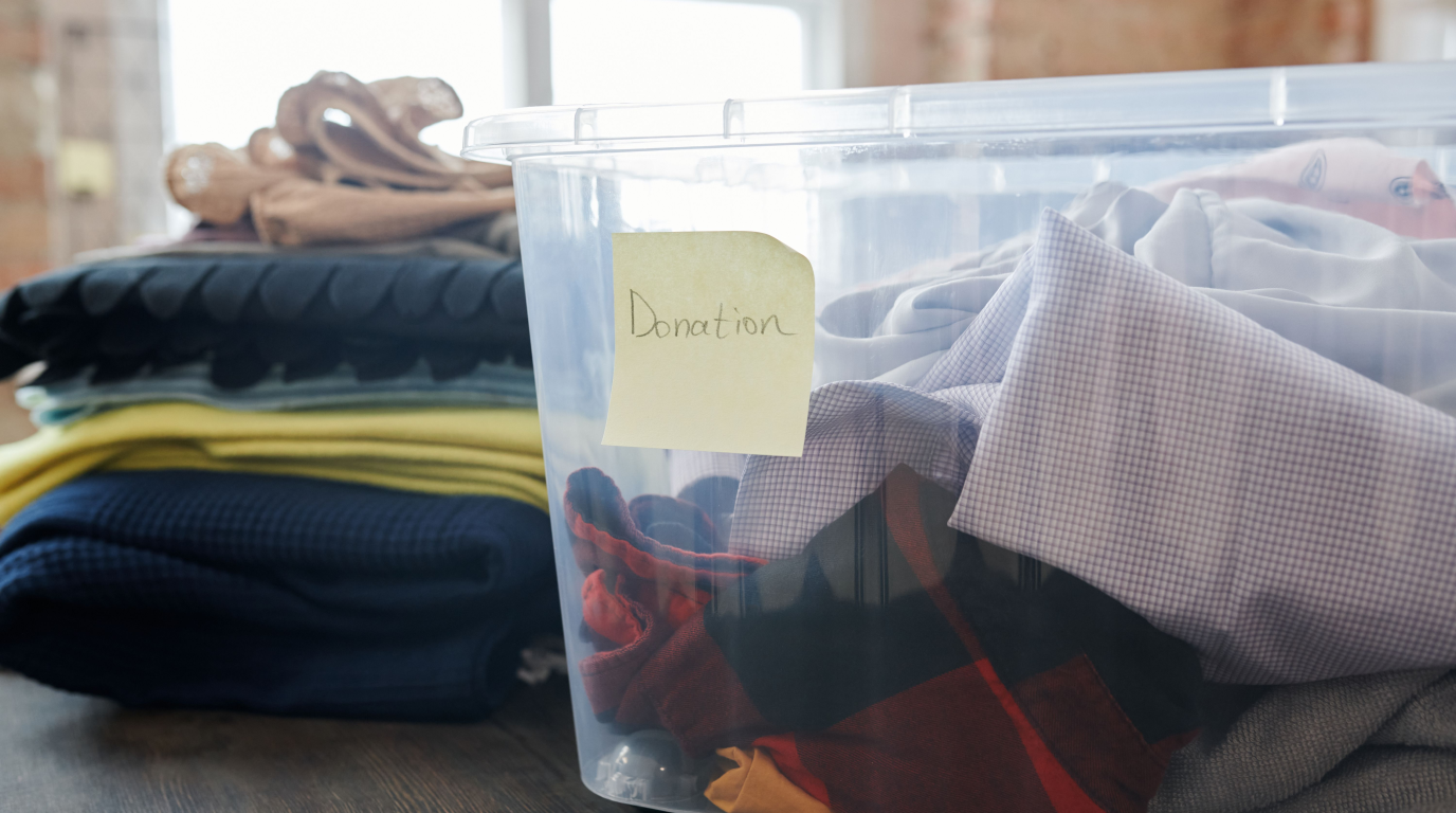 A clear plastic storage tote with a handwritten paper label and folded contents clearly visible through the side