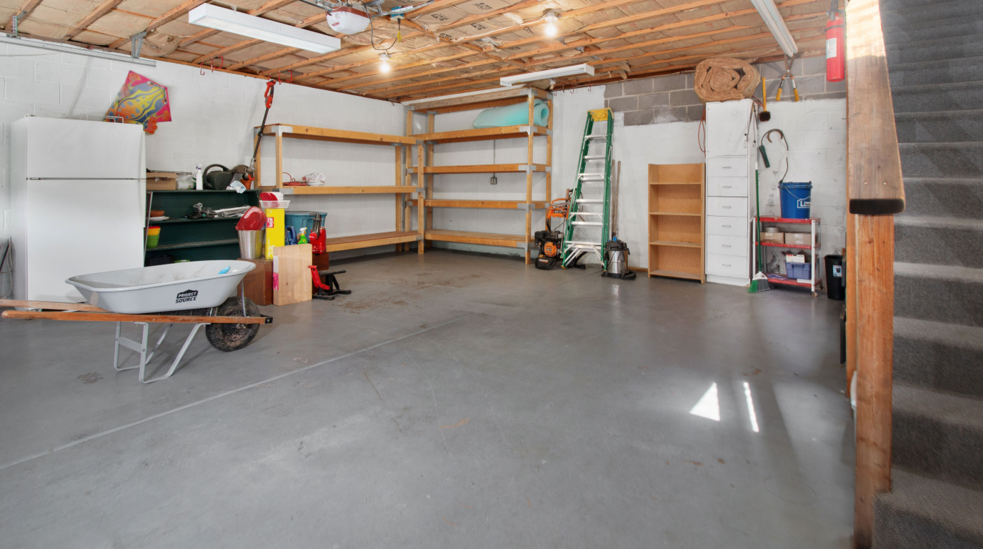 A tidy home garage with a pegboard tool wall, clear labeled bins on steel shelving, and a swept concrete floor with room to park a car